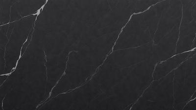 The primary subject of the image is a black marble countertop. The setting is a kitchen, with the countertop being the main focus of the scene. The visual style is a close-up of the marble countertop, showcasing its texture and details. The colors and mood of the image are predominantly dark, with the black marble countertop being the main source of contrast and visual interest.