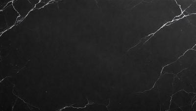 The primary subject of the image is a black marble countertop. The setting is a dark room, and the visual style is a close-up of the marble countertop. The colors and mood of the image are dark and moody, with the black marble countertop being the main focus.