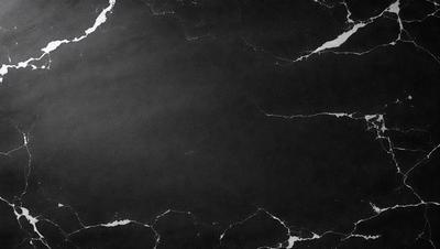 The primary subject of the image is a black marble countertop. The setting is a kitchen, with the countertop being the main focus of the scene. The visual style is a photo, capturing the marble countertop in detail. The colors and mood of the image are predominantly dark, with the black marble countertop being the most prominent feature.