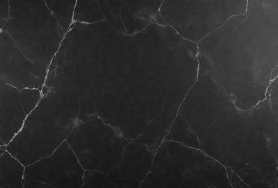 The primary subject of the image is a black marble countertop. The setting is a dark room, and the visual style is a close-up of the marble countertop. The countertop appears to be textured and has a dark, moody atmosphere.