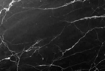 The image features a black marble countertop with a pattern of white veins. The countertop appears to be a part of a kitchen or bathroom setting. The visual style of the image is a close-up of the marble countertop, showcasing its unique texture and design. The colors in the image are predominantly black and white, giving the scene a sleek and modern appearance.