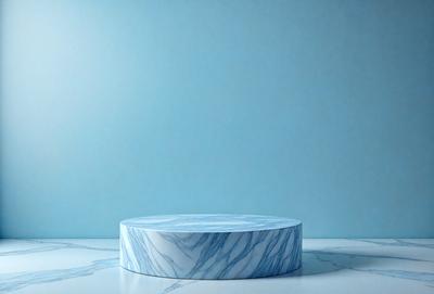 The primary subject of the image is a white marble tabletop. The tabletop is placed on a white marble countertop, which is situated in a room with a blue wall. The visual style of the image is a photo, and the dominant colors are white and blue. The overall atmosphere of the image is clean, elegant, and modern.