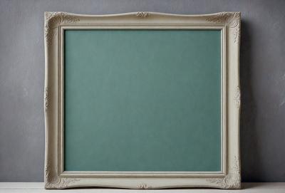 The primary subject of the image is a white frame with a green background. The setting is a room with a table, and the visual style is a photo. The colors and mood of the image are predominantly green, creating a calm and serene atmosphere.