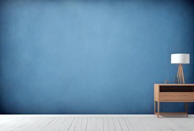 The primary subject of the image is a wooden table, which is placed against a blue wall. The setting appears to be a room with a wooden floor. The visual style of the image is a photo, capturing the wooden table and the blue wall in a realistic manner. The colors and mood of the image are predominantly blue, creating a calm and serene atmosphere.