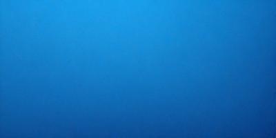 The primary subject of the image is a large, open, and dark blue sky. The setting is a vast, empty space with no visible landmarks or objects. The visual style is a natural, untouched, and unaltered representation of the sky. The colors and mood convey a sense of tranquility and vastness.