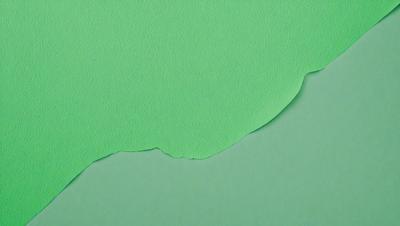 The primary subject of the image is a green piece of paper with a cutout of a green hill. The paper is placed on a green background, creating a visually appealing contrast. The visual style of the image is a combination of a photo and a drawing, as the paper appears to be a real piece of paper with a cutout, while the green hill has a digital art or illustration appearance. The colors and mood of the image are predominantly green, giving it a calm and serene atmosphere.