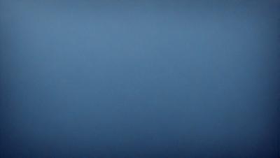 The primary subject of the image is a large, open, and dark blue sky. The setting is a vast, empty space with no visible landmarks or objects. The visual style is a natural, untouched landscape, and the colors and mood are predominantly dark and moody.
