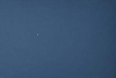 The primary subject of the image is a single planet, which is visible in the sky. The setting is a vast, open space with a clear blue sky. The visual style of the image is a photo, capturing the beauty of the planet against the backdrop of the sky. The colors and mood of the image are predominantly blue, creating a serene and peaceful atmosphere.