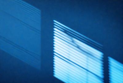 The primary subject of the image is a window with a blurred view of the outside. The setting is a dark room, and the visual style appears to be a photo. The colors and mood of the image are predominantly blue, creating a calm and serene atmosphere.