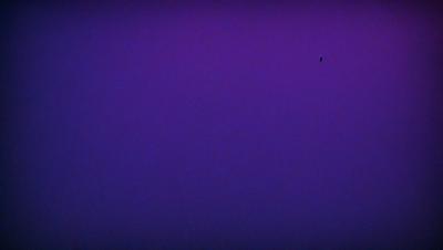 The primary subject of the image is a purple background. The setting is a dark, purple sky, which creates a moody atmosphere. The visual style is a photo, capturing the purple sky as the main focus. The colors and mood of the image are predominantly purple, giving it a dramatic and mysterious appearance.
