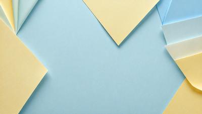 The primary subject of the image is a yellow piece of paper, which is placed on a blue surface. The setting appears to be a room with a blue wall. The visual style of the image is a photo, and the dominant colors are blue and yellow. The overall atmosphere of the image is calm and serene.