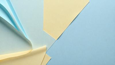 The primary subject of the image is a stack of yellow and blue colored paper. The setting is a blue background, and the visual style appears to be a photo. The colors and mood of the image are predominantly blue and yellow, creating a vibrant and lively atmosphere.