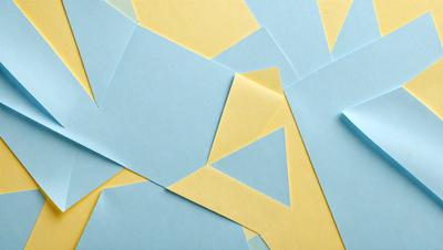 The primary subject of the image is a collection of blue and yellow triangles, which are cut out of paper. The setting is a blue and yellow background, creating a visually appealing contrast. The visual style is a combination of digital art and illustration, as the triangles are carefully cut and arranged. The colors and mood of the image are vibrant and lively, with the blue and yellow triangles creating a sense of energy and movement.