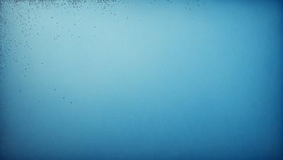 The primary subject of the image is a blue background with a few white specks. The setting is a blue sky, and the visual style is a photo. The colors and mood of the image are predominantly blue, creating a calm and serene atmosphere.