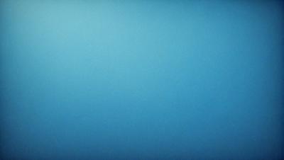 The primary subject of the image is a large, empty blue sky. The setting is a vast, open space with no visible landmarks or objects. The visual style is a realistic representation of the sky, with no indication of digital art or illustration. The colors and mood of the image are predominantly blue, creating a calm and serene atmosphere.