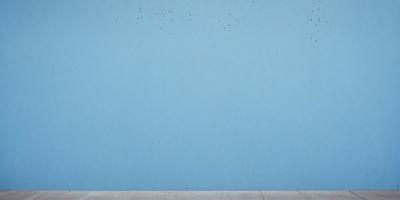 The primary subject of the image is a blue wall with a few white dots on it. The setting is a room with a blue wall, and the visual style appears to be a photo. The colors and mood of the image are predominantly blue, with the white dots adding a touch of contrast.