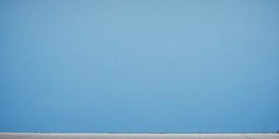 The primary subject of the image is a large, empty blue wall. The setting is a room with a blue background, and the visual style is a painting. The colors and mood of the image are predominantly blue, creating a calm and serene atmosphere.