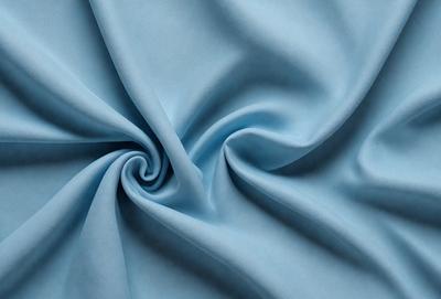 The primary subject of the image is a blue fabric, possibly a piece of cloth or a curtain. The setting is a room with a blue background, which creates a cohesive and visually appealing environment. The visual style is a close-up of the blue fabric, showcasing its texture and details. The colors and mood of the image are predominantly blue, creating a calm and serene atmosphere.
