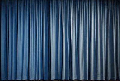 The primary subject of the image is a blue curtain. The setting is a stage or theater, with the curtains covering the stage. The visual style is a photo, and the dominant colors are blue and black. The overall atmosphere is dramatic and theatrical.
