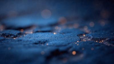 The primary subject of the image is a close-up of a blue surface with a pattern of tiny lights or sparkles. The setting appears to be a dark room, and the visual style is a combination of a photo and digital art. The dominant colors are blue and black, and the overall atmosphere is one of intrigue and beauty.