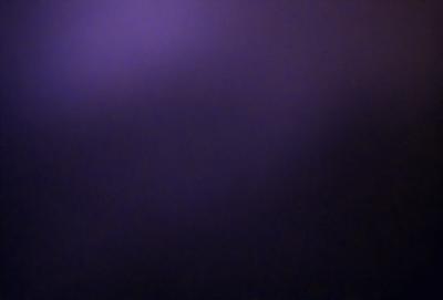 The primary subject of the image is a purple background. The setting is a dark, purple-colored room. The visual style is a close-up of the purple background, which creates a moody and atmospheric mood.