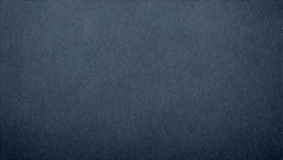 The primary subject of the image is a blue fabric, which appears to be a piece of denim. The setting is a dark background, which contrasts with the blue fabric. The visual style is a close-up of the fabric, showcasing its texture and color. The colors and mood of the image are predominantly dark and moody, with the blue fabric serving as the focal point.