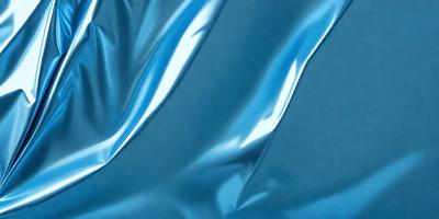 The primary subject of the image is a blue piece of fabric, which appears to be a piece of plastic or a shiny material. The setting is a dark background, which contrasts with the bright blue fabric. The visual style is a close-up of the fabric, showcasing its texture and shine. The colors and mood of the image are predominantly blue, creating a calm and serene atmosphere.