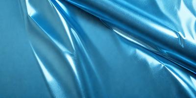 The primary subject of the image is a blue fabric, which appears to be a piece of silk. The setting is a close-up view of the fabric, showcasing its texture and color. The visual style is a realistic representation of the fabric, with no indication of digital art or illustration. The colors and mood of the image are predominantly blue, creating a calm and serene atmosphere.