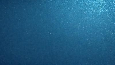 The primary subject of the image is a blue background with a pattern of glittering stars. The setting is a dark, starry night, and the visual style is a combination of a photo and digital art. The colors and mood of the image are predominantly dark and mysterious, with the blue background and glittering stars creating a sense of depth and intrigue.