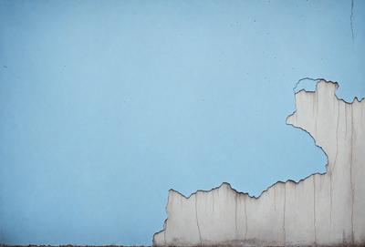 The primary subject of the image is a blue wall with a crack in it. The setting is an outdoor environment, and the visual style appears to be a photo. The dominant colors are blue and white, creating a calm and serene atmosphere.