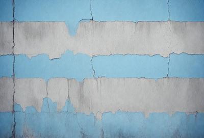 The primary subject of the image is a blue wall with peeling paint, giving it a worn and aged appearance. The setting is a room with a blue wall, and the visual style is a photo. The dominant colors are blue and white, creating a calm and soothing atmosphere.