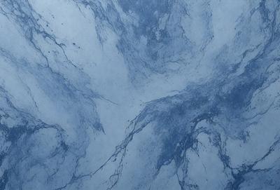 The primary subject of the image is a blue marble wall with a pattern of swirls and ripples. The setting is a room with a blue-toned atmosphere. The visual style is a close-up of the marble wall, showcasing the intricate design. The colors and mood are predominantly blue, creating a serene and calming environment.