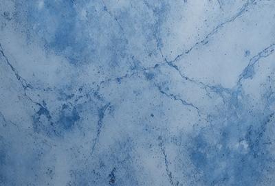 The primary subject of the image is a blue marble wall with a pattern of white and blue streaks. The setting is a room with a blue marble wall, and the visual style is a photo. The dominant colors are blue and white, creating a calm and serene atmosphere.