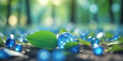 The primary subject of the image is a blue glass ball, which is placed on a leaf. The setting is a forest, with trees visible in the background. The visual style is a photo, capturing the natural beauty of the scene. The colors and mood are predominantly blue, creating a serene and calming atmosphere.