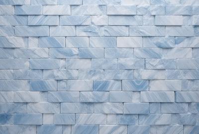 The primary subject of the image is a blue and white marble wall. The setting is a room with a blue brick wall, and the visual style is a photo. The dominant colors are blue and white, creating a calm and serene atmosphere.