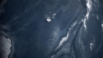 The primary subject of the image is a large, dark blue body of water with a few small white objects floating on the surface. The setting is a vast, open body of water, and the visual style appears to be a combination of a photo and a digital art or illustration. The colors and mood of the image are dark and moody, with the blue water and white objects creating a sense of depth and mystery.