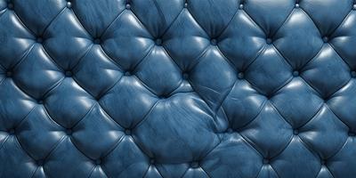 The primary subject of the image is a blue leather couch with a blue velvet-like texture. The setting is a room with a blue background, which adds to the overall atmosphere. The visual style is a close-up of the couch, showcasing its unique texture and design. The colors and mood of the image are predominantly blue, creating a calm and relaxing environment.
