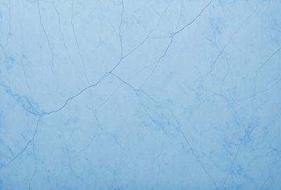 The primary subject of the image is a blue marble wall with a cracked and chipped appearance. The setting is a room with a blue background. The visual style is a close-up of the wall, showcasing its unique texture and appearance. The colors and mood of the image are predominantly blue, giving it a calm and serene atmosphere.