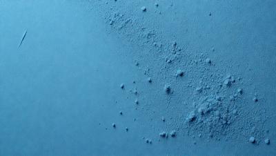 The primary subject of the image is a close-up of a blue surface, possibly a wall or a piece of fabric, with a pattern of bubbles or dots on it. The setting appears to be indoors, with the blue surface being the main focus of the image. The visual style is a close-up, which emphasizes the details of the blue surface and the pattern of bubbles or dots. The colors and mood of the image are predominantly blue, creating a calm and serene atmosphere.