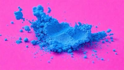 The primary subject of the image is a blue powder, which is scattered on a pink surface. The setting appears to be a laboratory or a workspace, as the blue powder is being used for a specific purpose. The visual style of the image is a close-up of the blue powder, showcasing its texture and color. The dominant colors in the image are blue and pink, creating a vibrant and lively atmosphere.