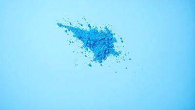 The primary subject of the image is a blue powder or substance, which appears to be a powdered substance or a blue powder. The setting is a blue background, which creates a contrast with the blue substance. The visual style of the image is a close-up of the blue substance, showcasing its texture and color. The colors and mood of the image are predominantly blue, giving it a calm and serene atmosphere.