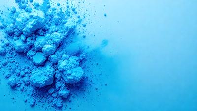 The primary subject of the image is a blue powder, which appears to be a powdered substance or a blue paint. The setting is a white background, which provides a clean and uncluttered environment for the powder to be displayed. The visual style of the image is a close-up of the powder, showcasing its texture and color. The dominant colors in the image are blue and white, creating a calm and serene atmosphere.