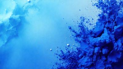 The primary subject of the image is a blue, swirling, and cloudy mass. The setting is a blue background, which creates a contrasting and visually appealing scene. The visual style is a combination of a photo and digital art, as the blue mass appears to be a digital creation. The colors and mood of the image are predominantly blue, creating a sense of calmness and tranquility.