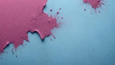 The primary subject of the image is a pink substance, possibly a liquid or a powder, that is splattered or spilled onto a blue surface. The setting appears to be a table or a countertop, with the blue background providing a contrasting color to the pink substance. The visual style of the image is a close-up, focusing on the pink substance and its interaction with the blue surface. The colors and mood of the image are predominantly pink and blue, creating a vis