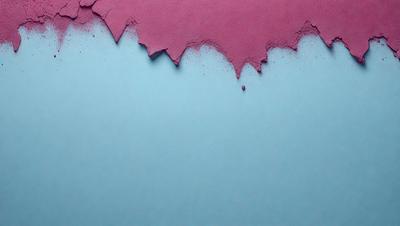 The primary subject of the image is a piece of pink paper with a blue background. The paper appears to be peeling or falling apart, creating a sense of decay or aging. The setting is a blue surface, which contrasts with the pink paper. The visual style is a close-up of the paper, emphasizing its texture and the peeling process. The colors and mood of the image are predominantly blue and pink, with a sense of fragility and vulnerability.
