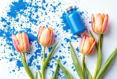 The primary subject of the image is a vase filled with blue flowers, which are placed on a table. The setting is a white background, and the visual style appears to be a photo. The dominant colors in the image are blue and pink, creating a calm and serene atmosphere.