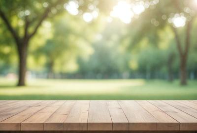 The primary subject of the image is a wooden bench situated in a grassy field. The setting is a park with trees in the background, providing a serene and natural atmosphere. The visual style is a photo, capturing the outdoor scene with the bench as the main focus. The colors and mood of the image are predominantly green, with the grass and trees creating a sense of tranquility and relaxation.