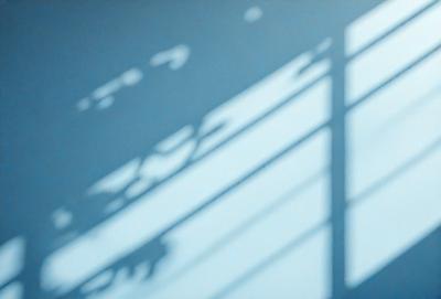 The primary subject of the image is a shadow of a person cast on a wall. The setting is a room with a window, and the visual style appears to be a photo. The colors in the image are predominantly blue, and the overall atmosphere is calm and serene.