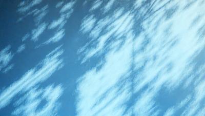 The primary subject of the image is a cloudy blue sky with white clouds. The setting is a vast, open space with no visible landmarks or objects. The visual style is a natural, outdoor scene with a focus on the clouds and sky. The colors and mood are predominantly blue and white, creating a serene and peaceful atmosphere.