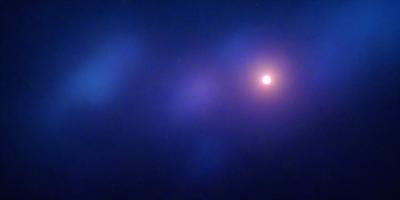 The primary subject of the image is a bright, glowing sun. The setting is a dark, starry sky, with the sun being the main focus of the scene. The visual style is a photo, capturing the beauty of the sun and its surroundings. The colors and mood of the image are predominantly dark and moody, with the sun being the only source of light and warmth in the scene.
